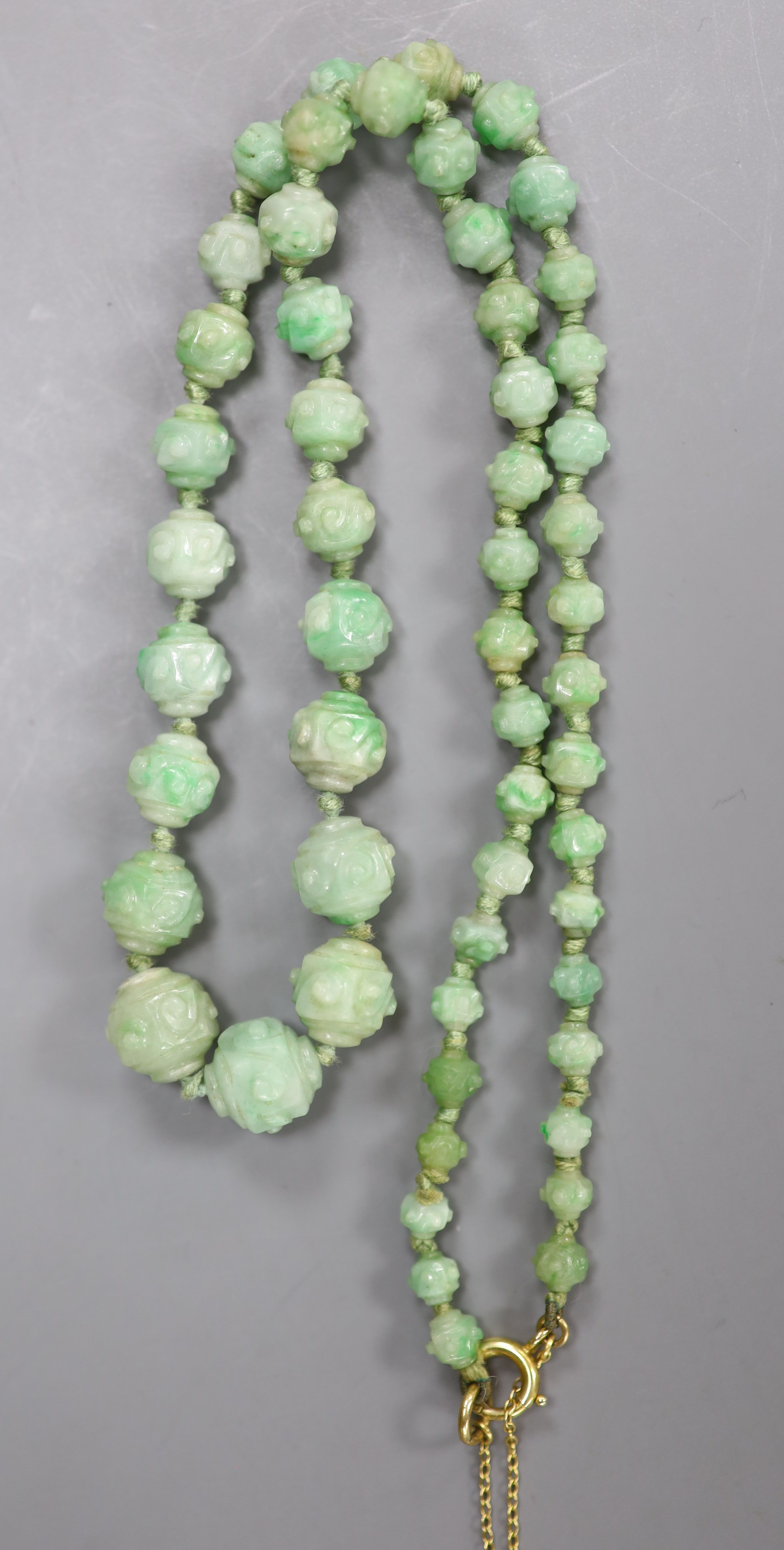 An early 20th century graduated carved jade bead necklace, with 9ct clasp, 47cm, gross weight 30 grams.